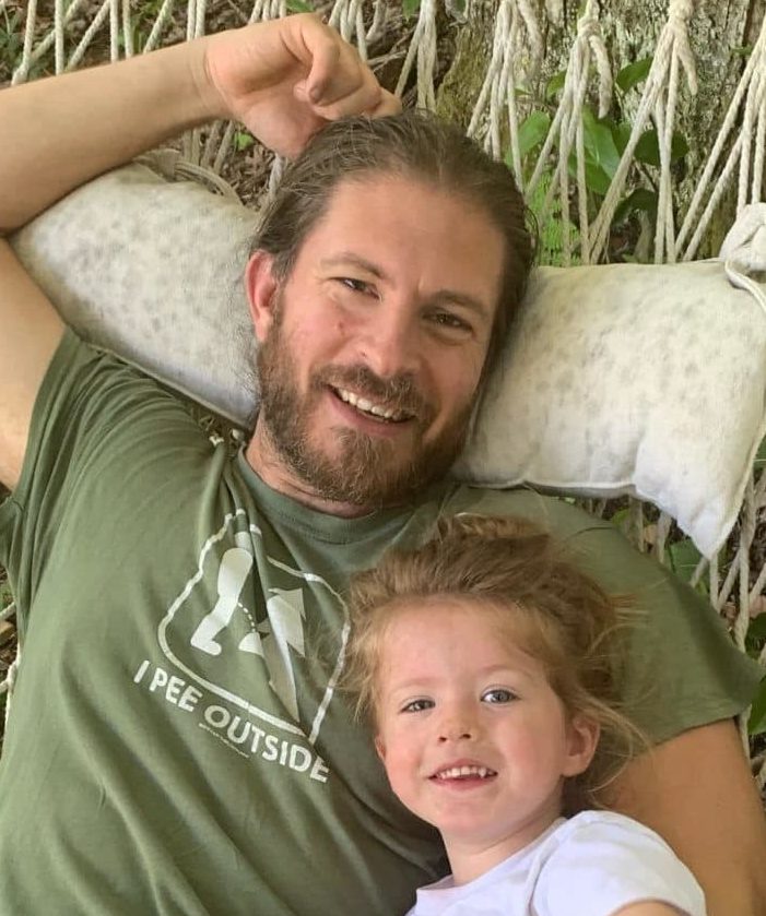 Man with his child in a hammock smiling